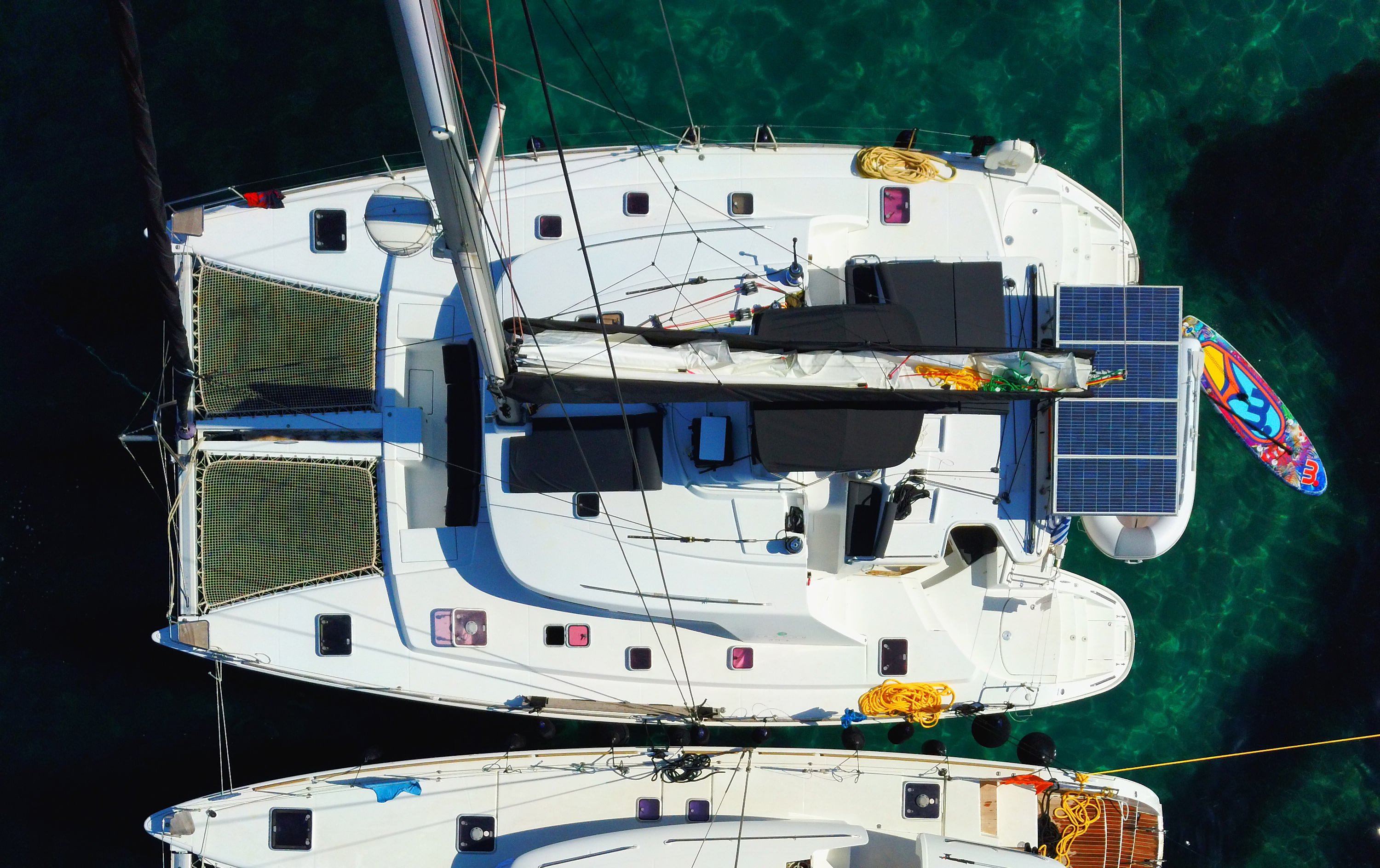 Guests relaxing on a catamaran deck under blue Mediterranean skies